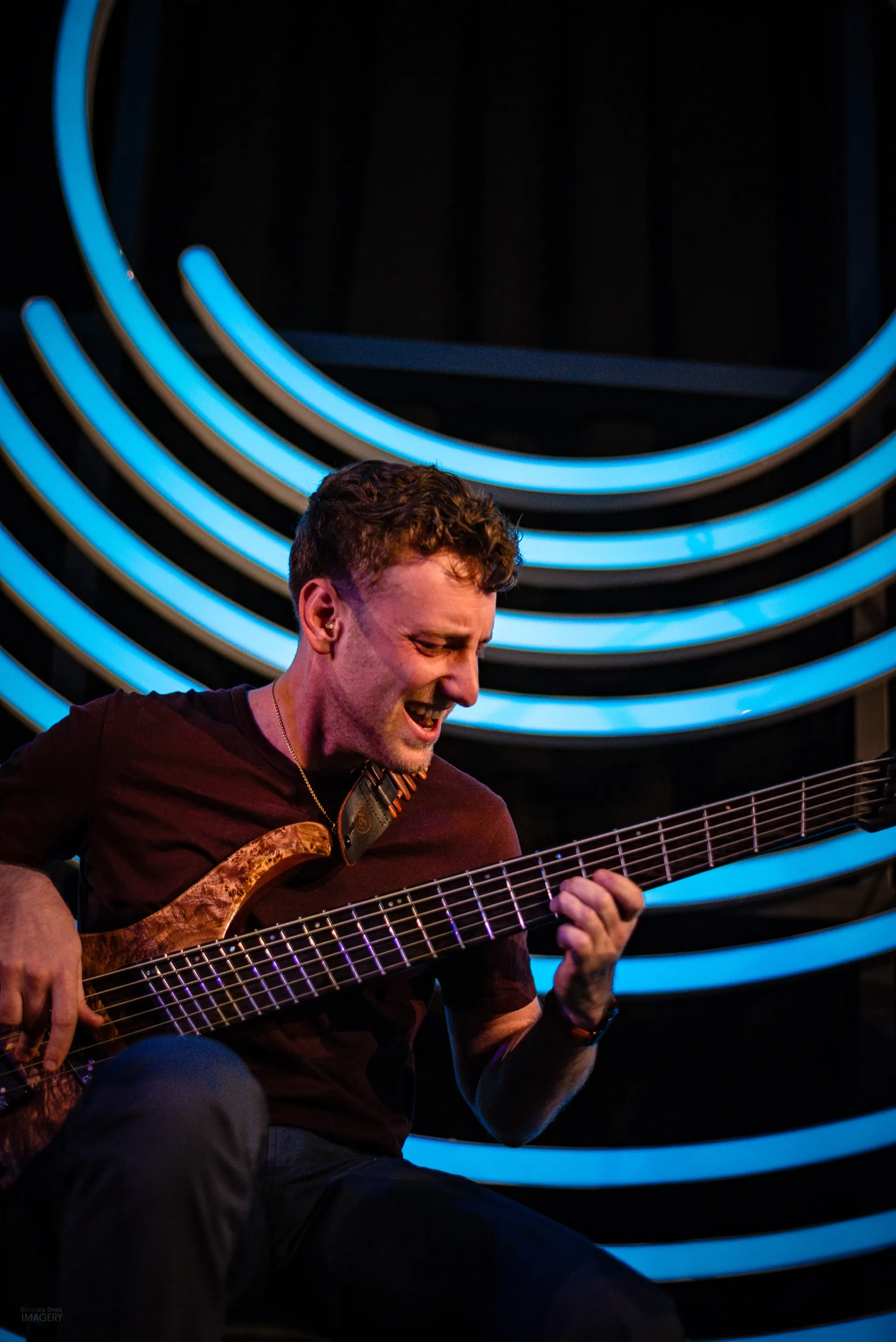 Jordan Lovinger close-up playing bass at Dazzle Denver — six-string bass with neon lighting