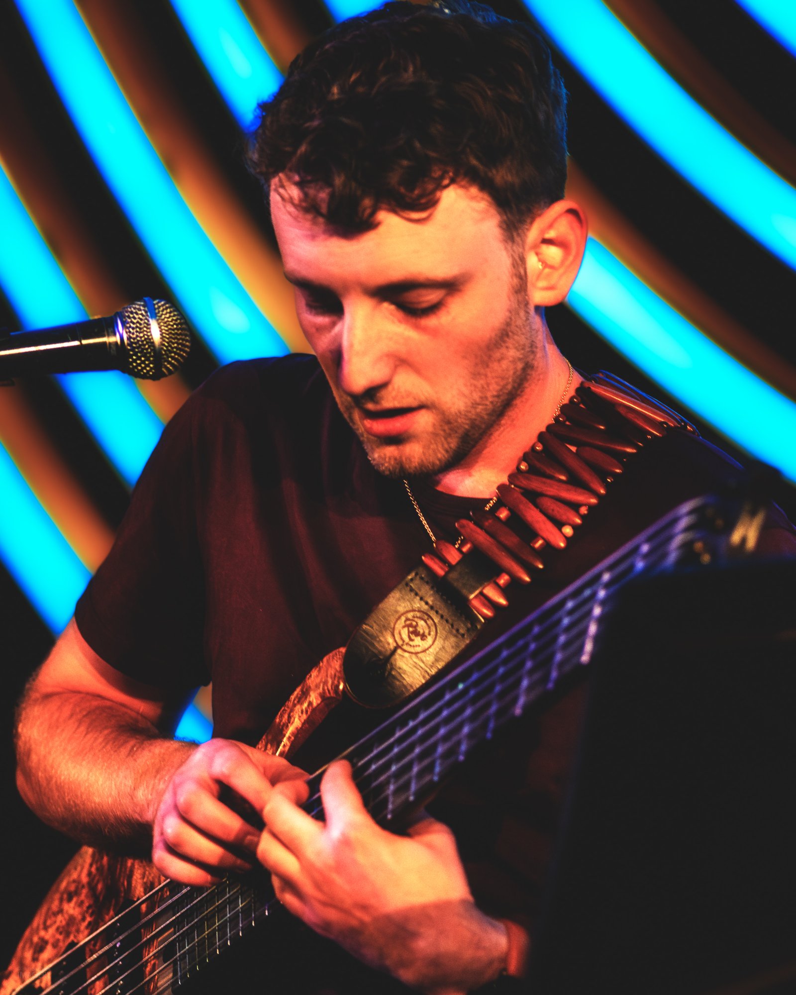 Jordan Lovinger playing bass at Dazzle Denver with neon background