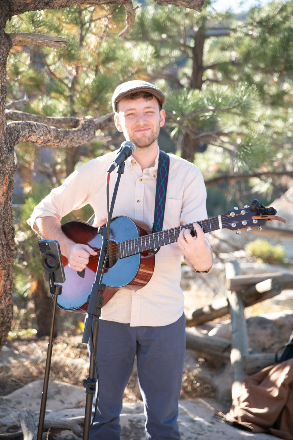 Wedding guitarist Jordan Lovinger smiling warmly while performing at an outdoor mountain wedding ceremony in Colorado